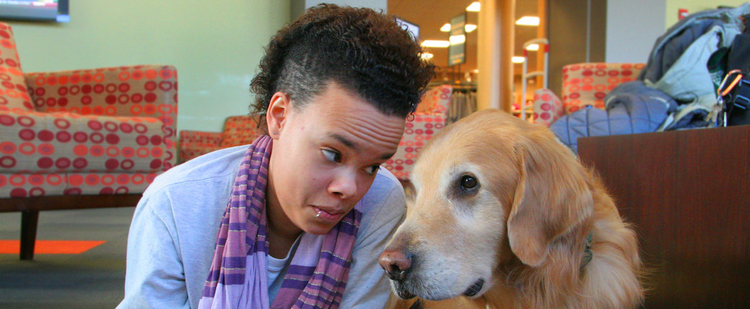 black woman lying on the floor next to a therapy dog