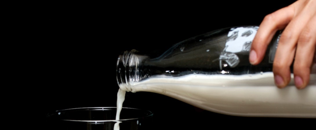 milk being poured from glass bottle into a glass