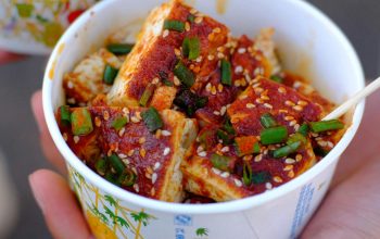 close-up of hand holding cup with tofu dish China