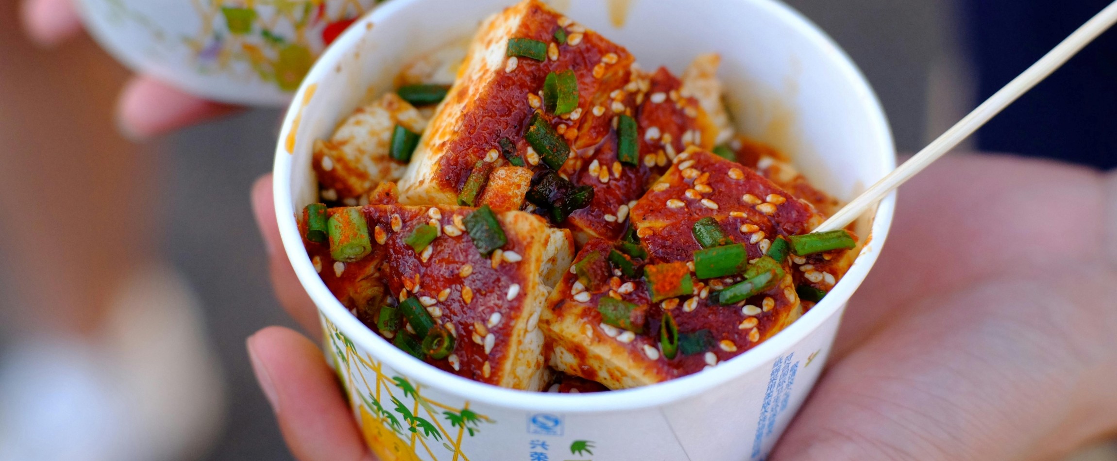 close-up of hand holding cup with tofu dish China