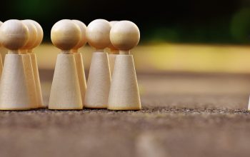 group of wooden figures with one standing alone