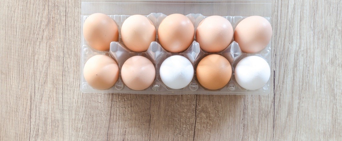 a carton of ten eggs on a wooden board