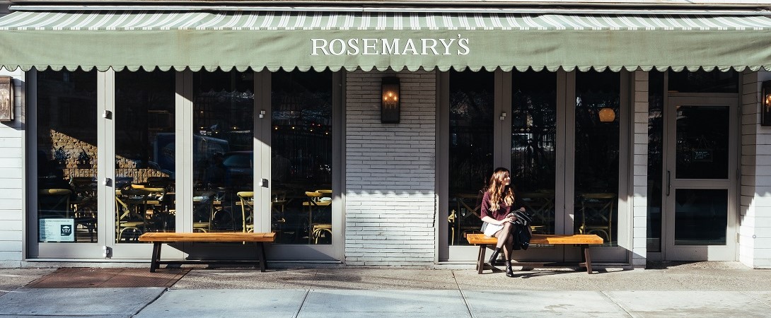 a woman sitting outside a Rosemary's restaurant