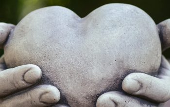 stone sculpture of two hands holding heart