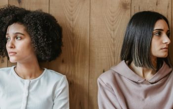 two people leaning against wall staring in opposite directions